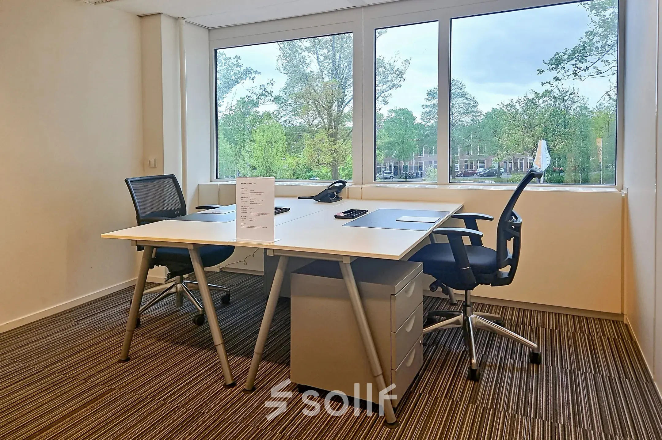 A bright office space at Poortweg 4, Delft, with two desks and chairs facing a large window, ideal for office space rental.