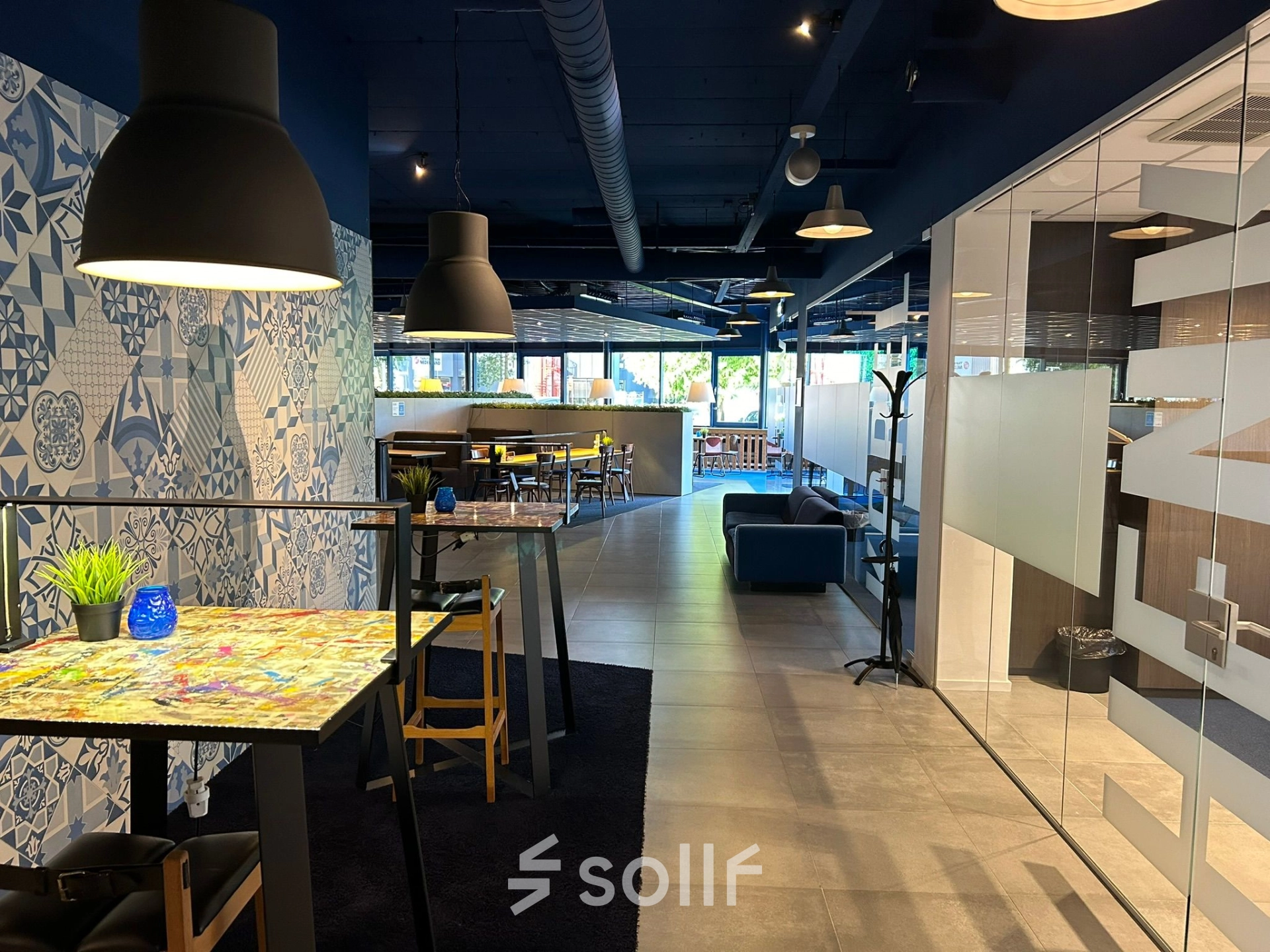 Office space at Amerikastraat 3 in Den Bosch featuring a modern interior with artistic decor and several workspaces. Ideal for office space rental with natural light and stylish furnishings.