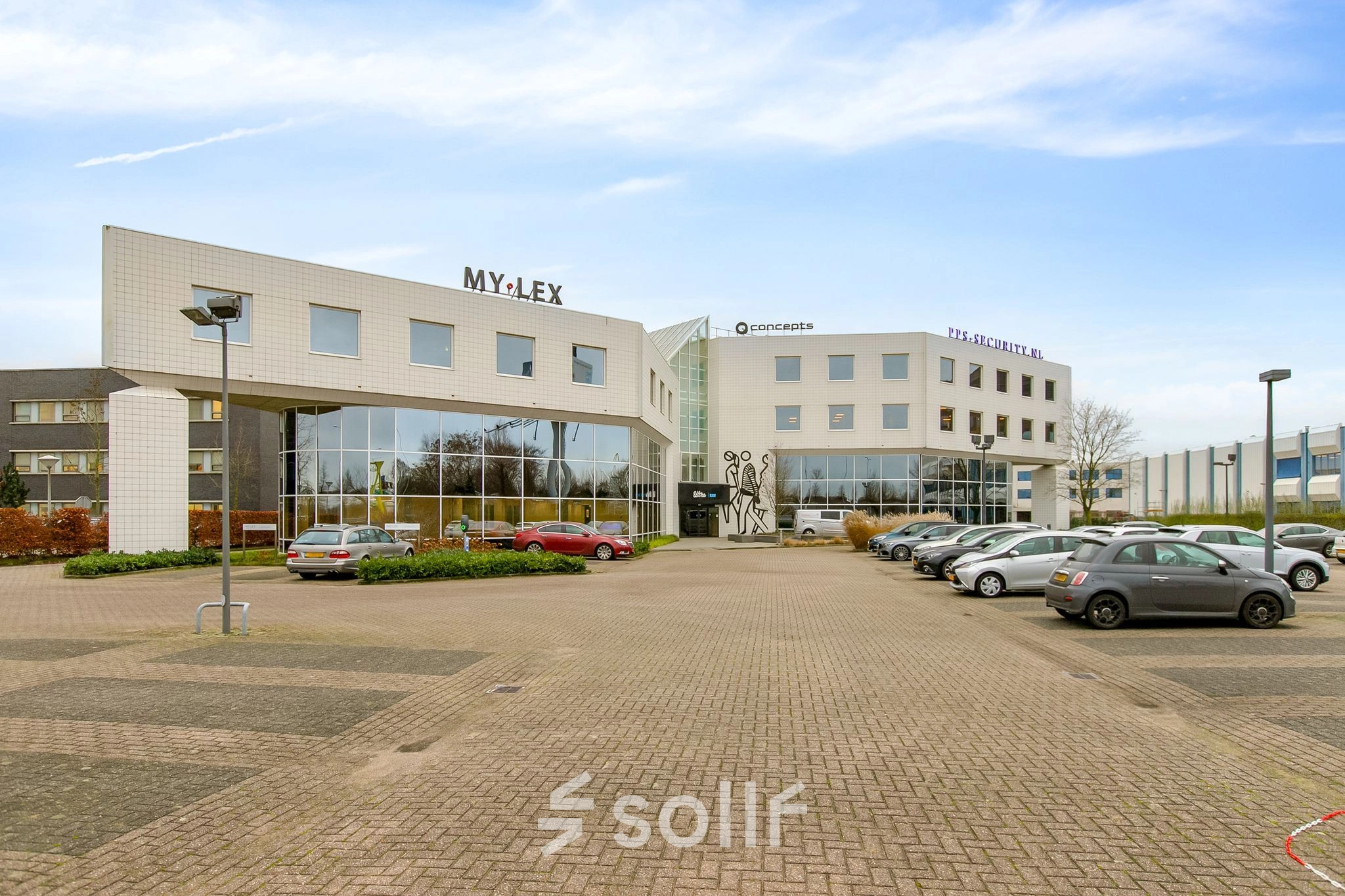 Exterior view of an office building at Europalaan 6, Den Bosch, featuring a modern facade and ample parking space. Ideal for businesses seeking office space rental in a convenient location.