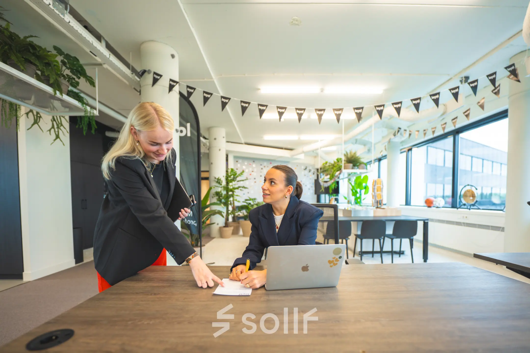 Two people in a modern office at Hambakenwetering 1, Den Bosch are engaged in a business discussion in a lively workspace, ideal for office space rental.