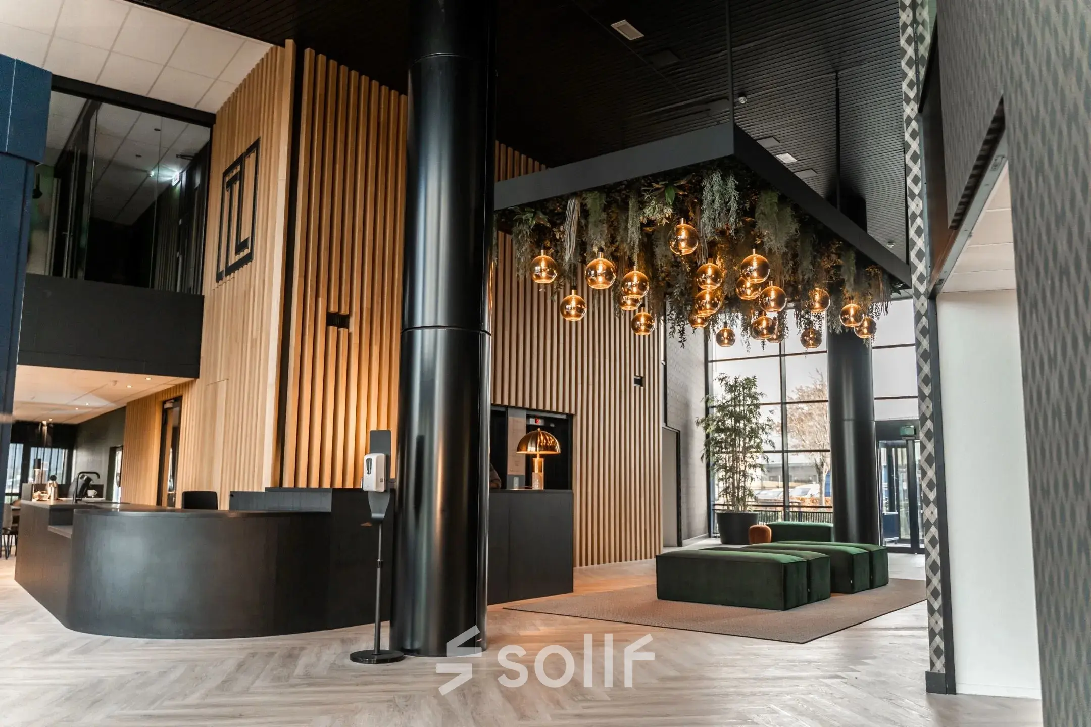 Modern office lobby at Reitschweg 1, Den Bosch, featuring stylish hanging lights and green seating area, available for office space rental.