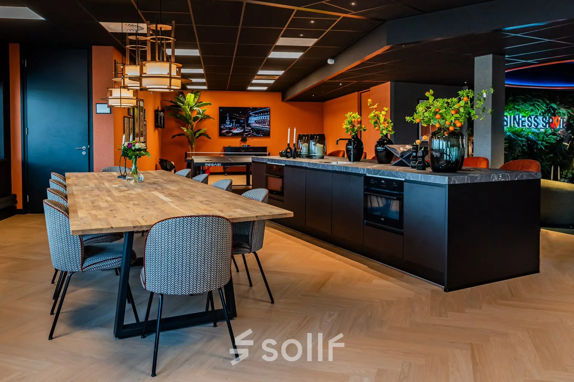 Modern office kitchen with a wooden dining table, stylish chairs, and a sleek kitchenette at Reitschweg 1, Den Bosch, ideal for office space rental.