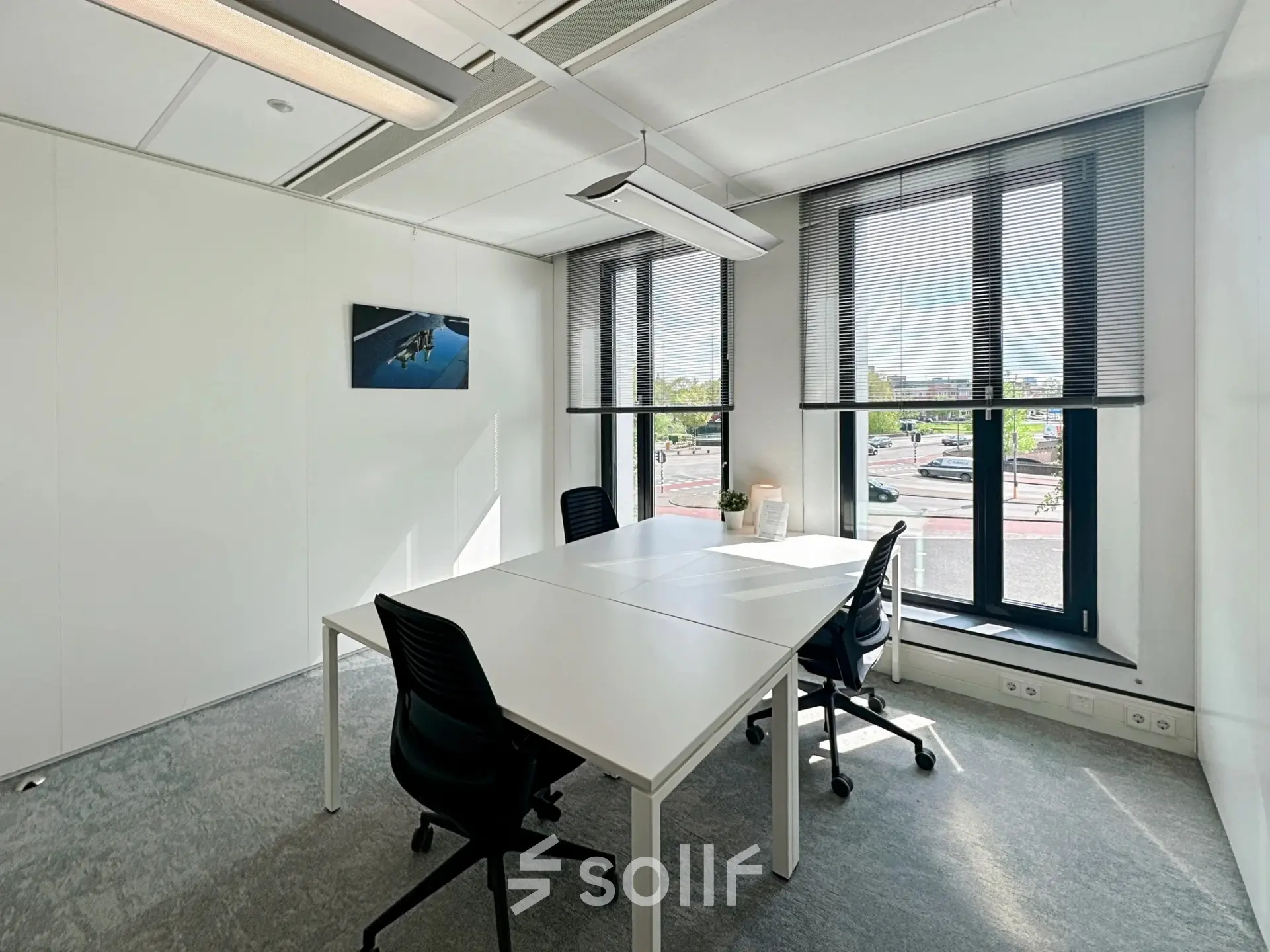 Bright office space for rent at Willemsplein 2, Den Bosch, featuring large windows, modern lighting, and a table with chairs, ideal for meetings.