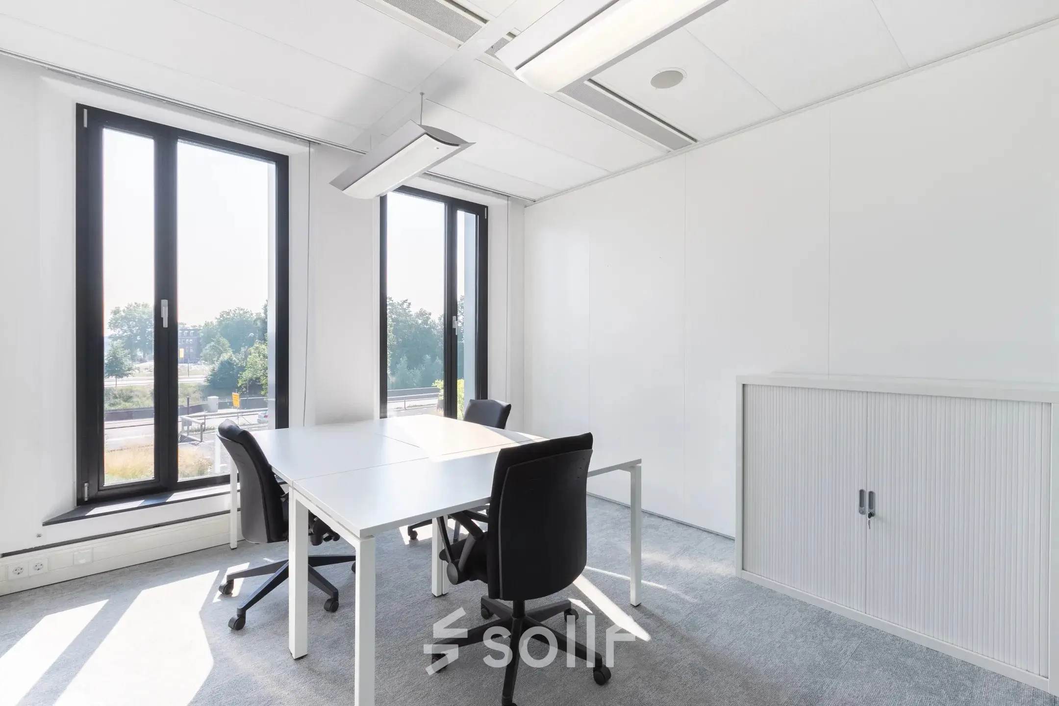 Bright office space at Willemsplein 2, Den Bosch, featuring minimalist furniture and large windows with city views, ideal for office space rental.