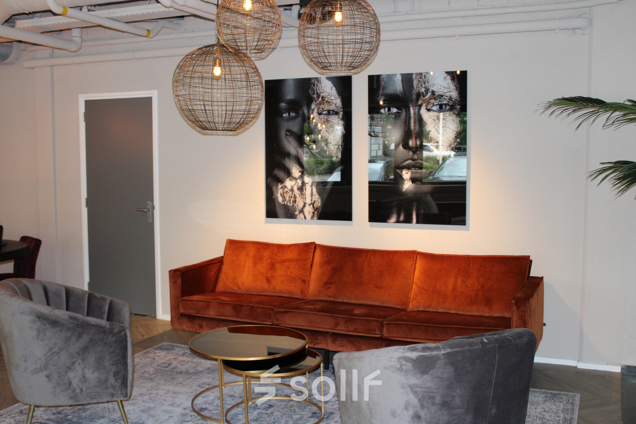 Stylish office space for rent at Keulenstraat 1, Deventer, featuring elegant seating with art-adorned walls and modern lighting.