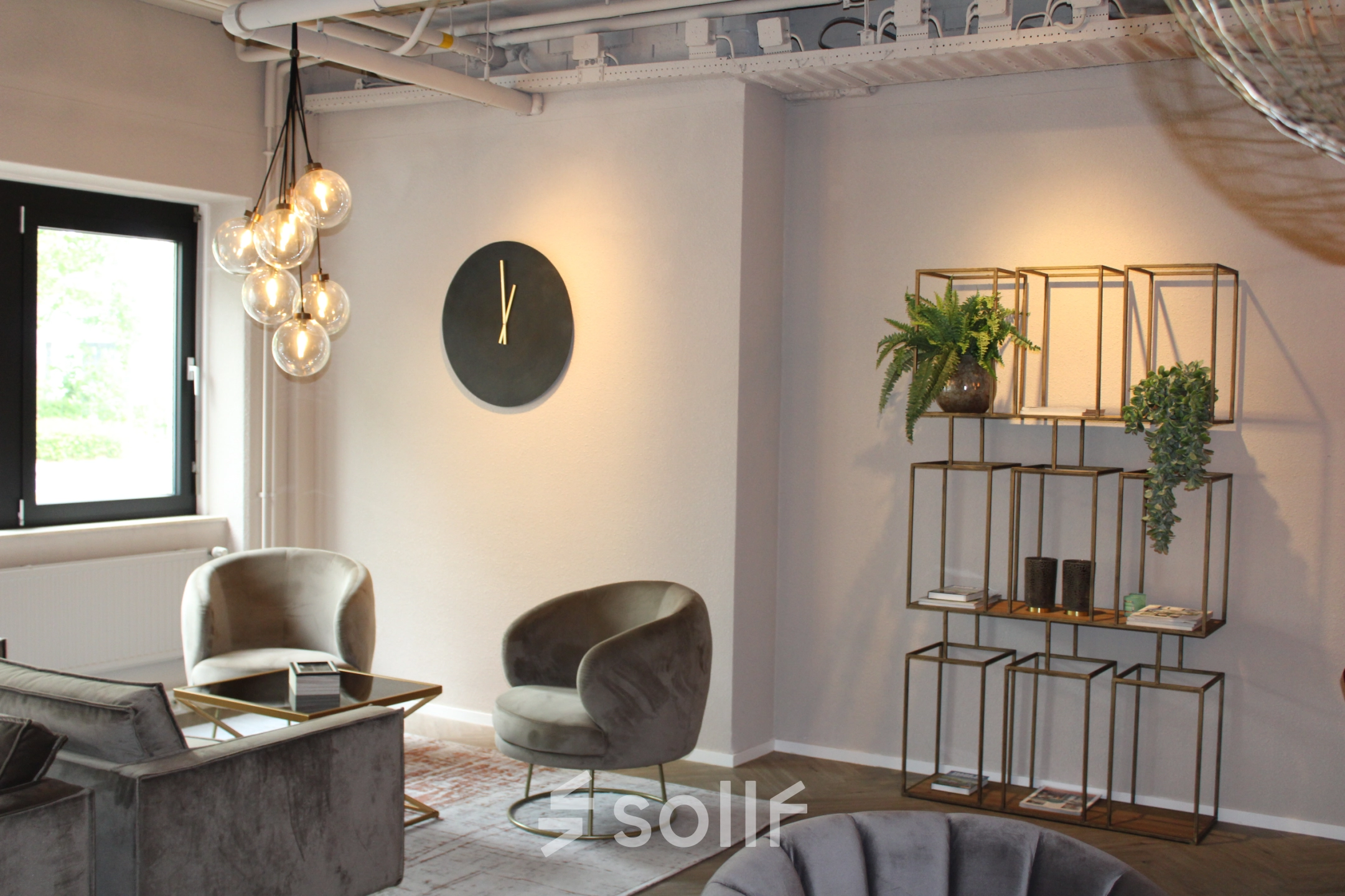 Modern, furnished office lounge at Keulenstraat 1, Deventer, suitable for office space rental with stylish seating and decorative shelving.