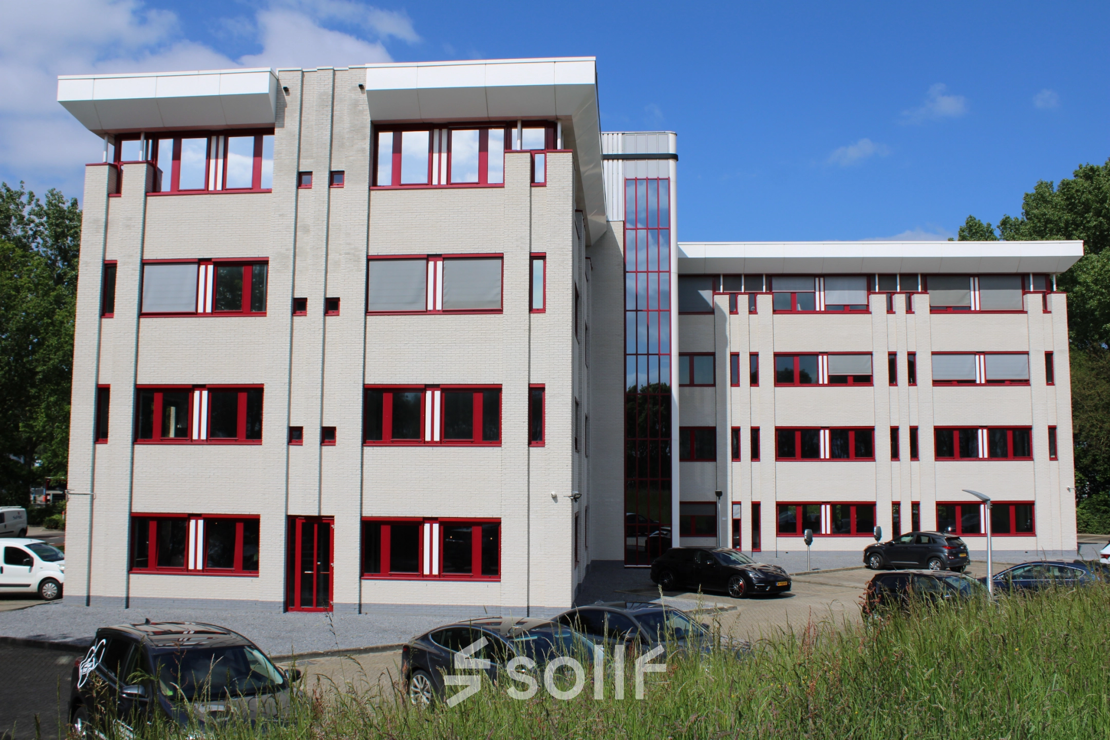 Exterior view of an office building for rent at Keulenstraat 1, Deventer, featuring a modern facade with red-framed windows and parking space in front.