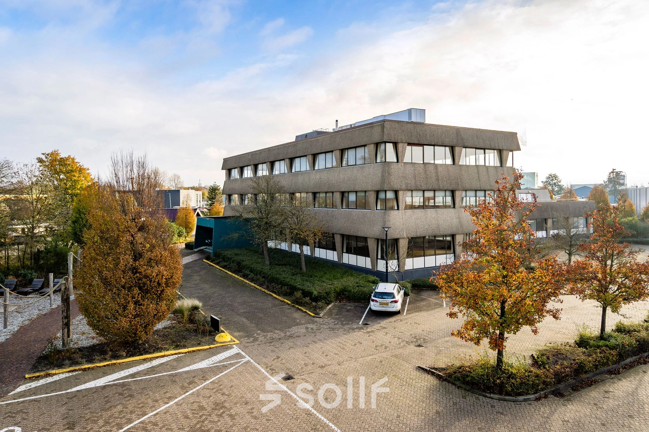 Exterior view of an office building at Staverenstraat 15-17 in Deventer with surrounding autumn trees. Ideal for office space rental.