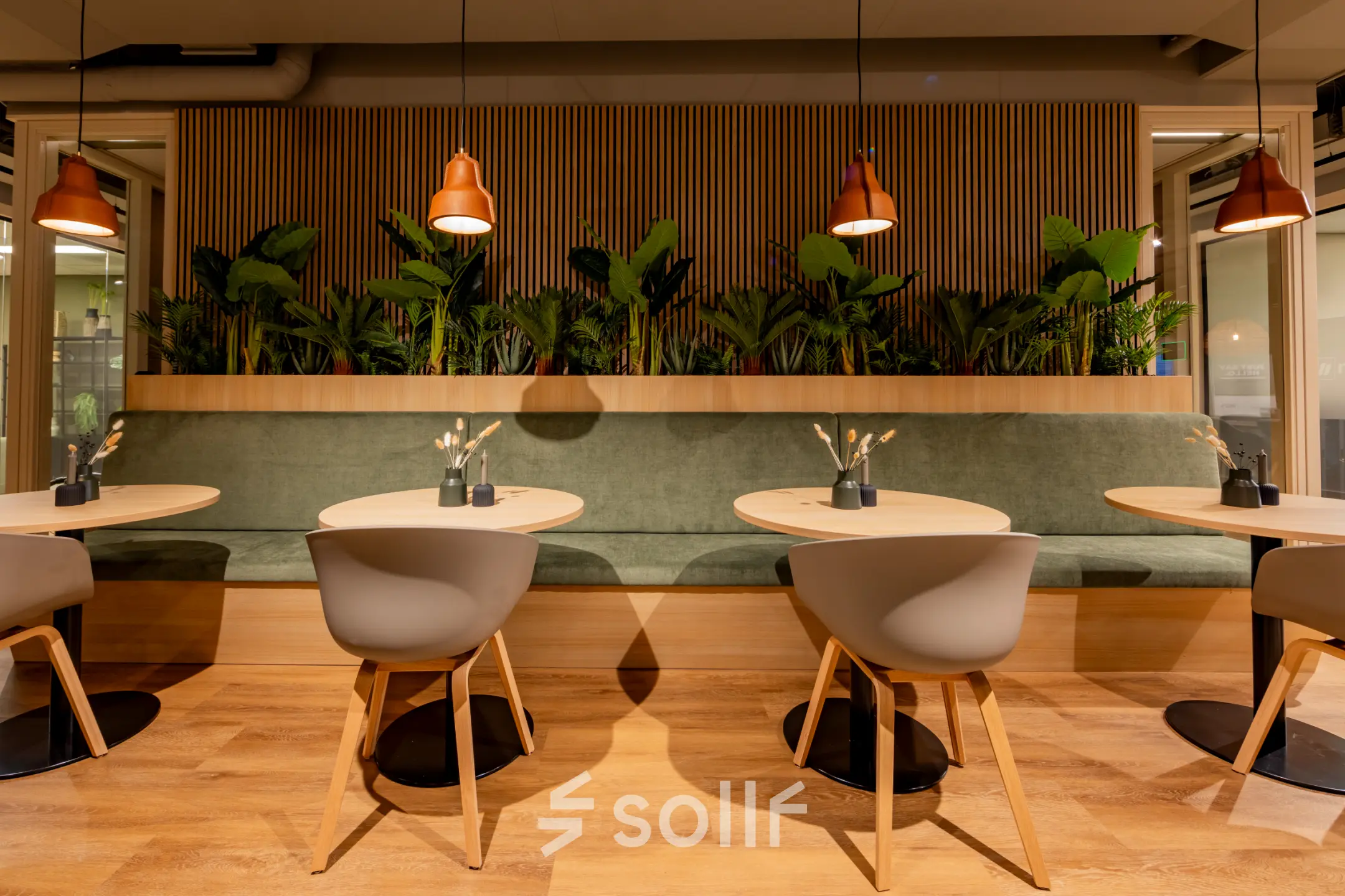 Modern office space at Diemerhof 42, Diemen, featuring a stylish seating area with round tables, chairs, and indoor plants for a comfortable workspace. Ideal for office space rental.