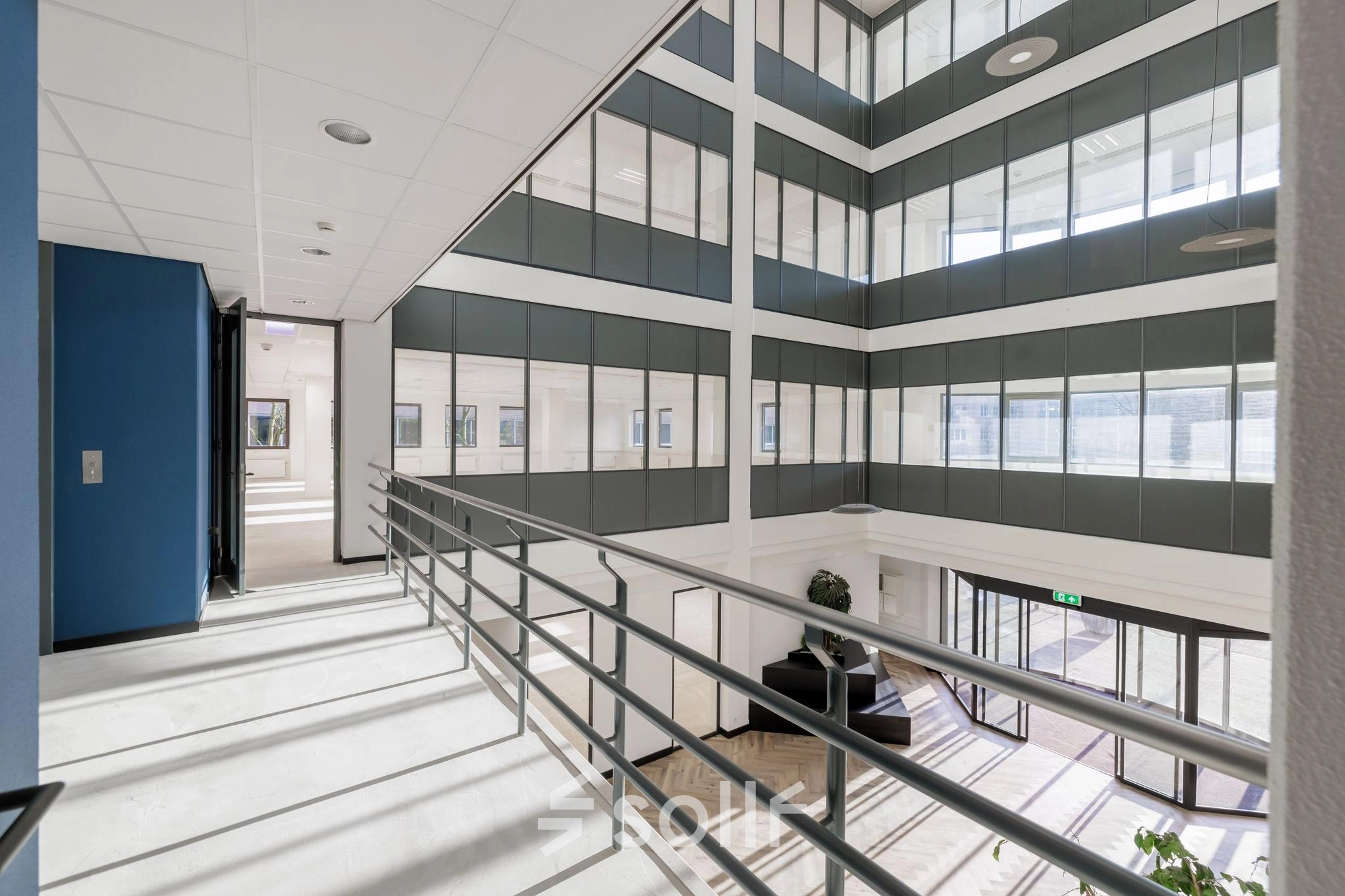 Bright and spacious interior hall with large windows and a view of a multi-story office structure, ideal for office space rental at Wisselwerking 40-48, Diemen.
