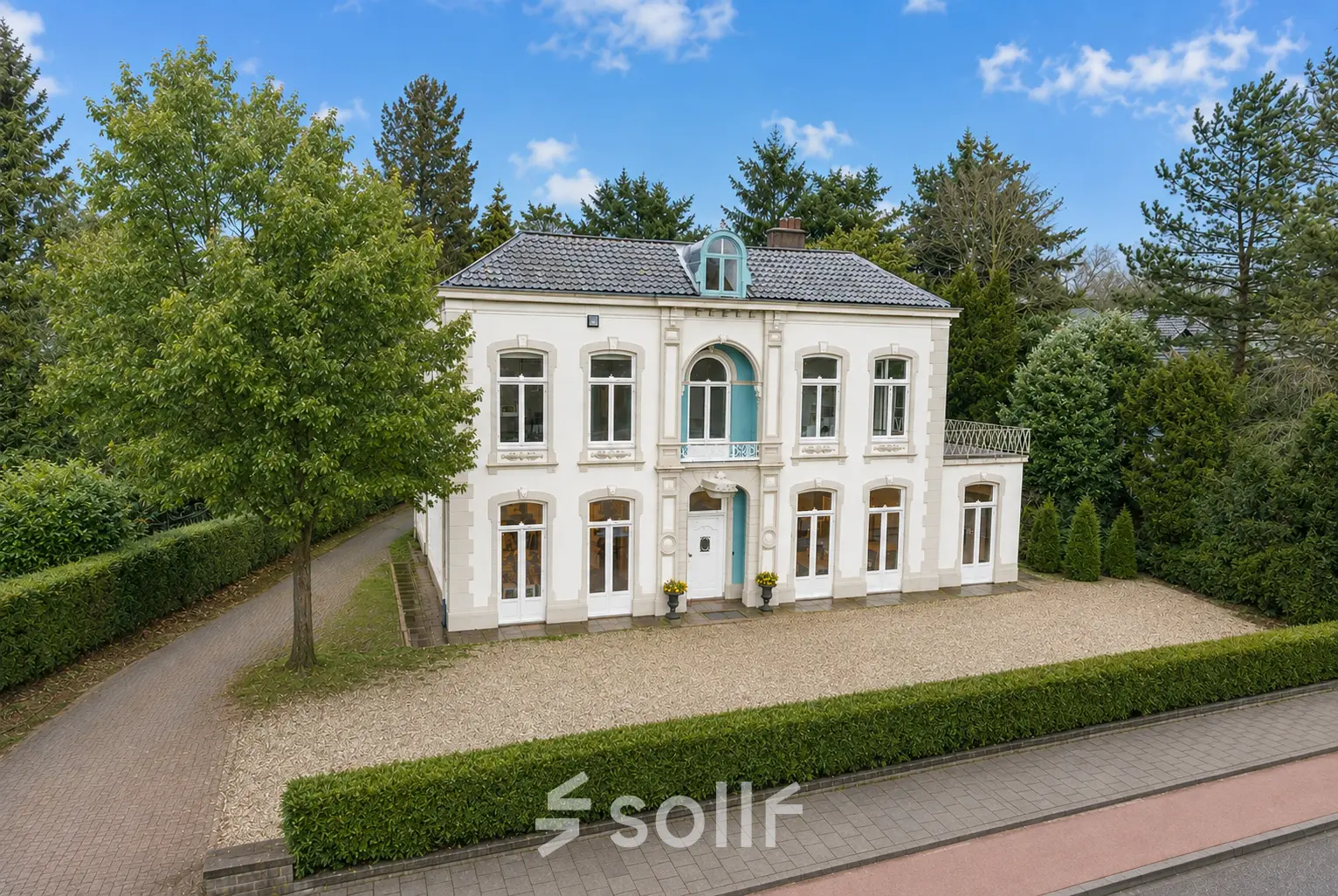 Charming exterior view of an office space rental at Dorpsstraat 77, Doorn, showcasing a classic white building surrounded by greenery.