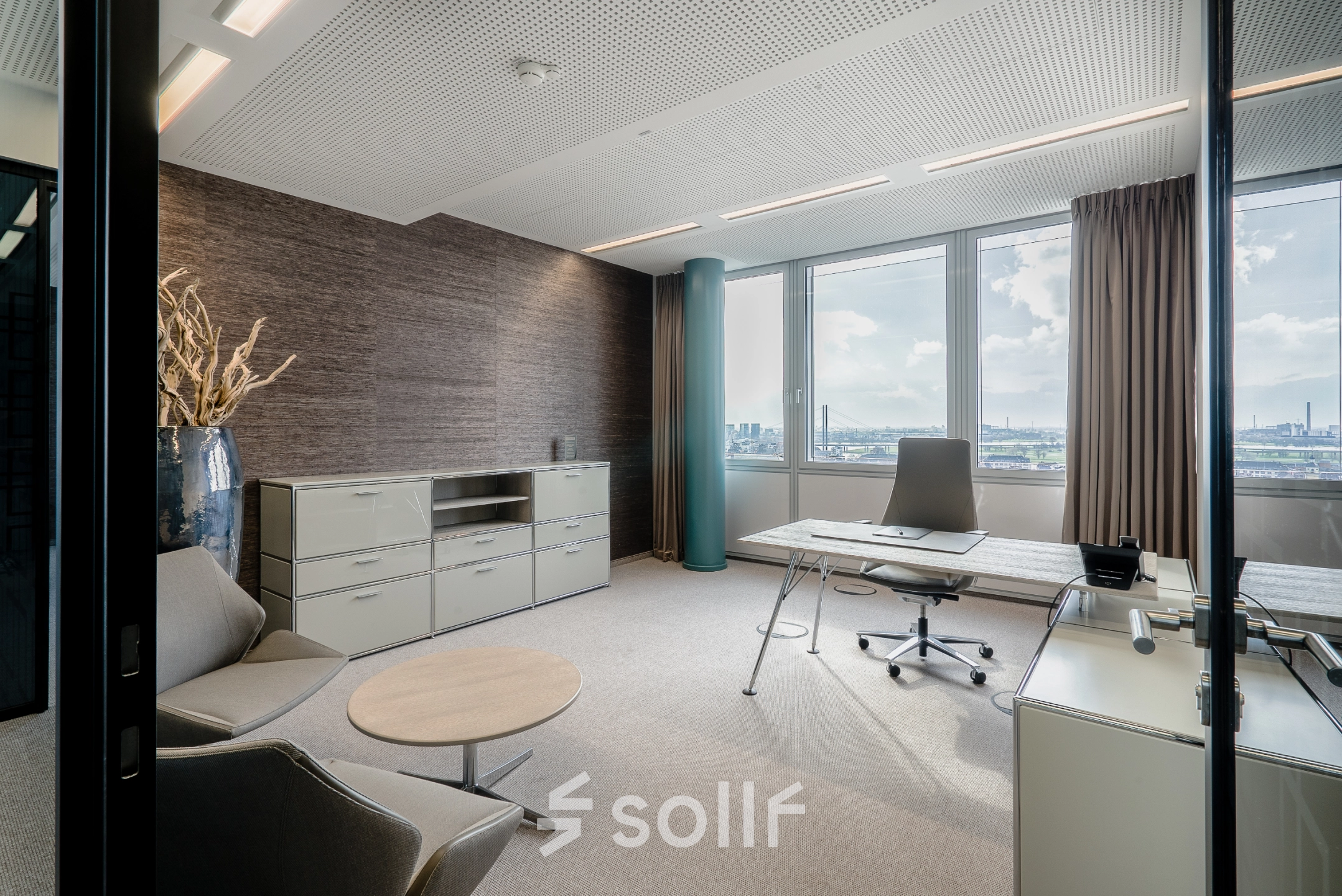 Bright, stylish furnished office at Dreischeibenhaus 1, Düsseldorf Old Town with a large window view, modern desk, and comfortable chairs. Perfect for your next office space rental.