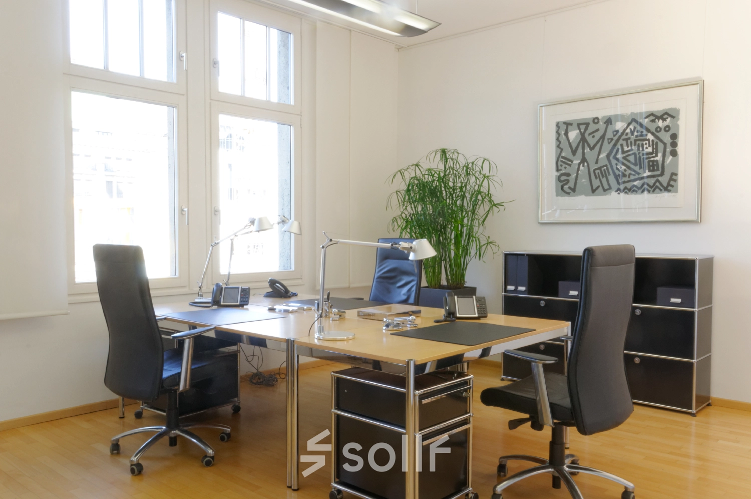 Bright, furnished office space rental at Königsallee 14, Düsseldorf Old Town, featuring two sleek desks, executive chairs, and a large window enhancing natural light.