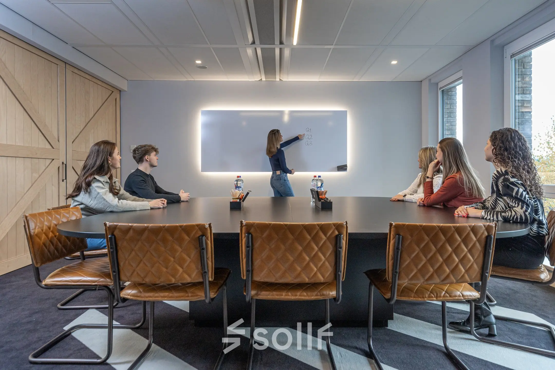 A modern conference room at Flight Forum 120-159, Eindhoven Airport, with attendees engaged in a meeting around a large table, exemplifying ideal office space rental.