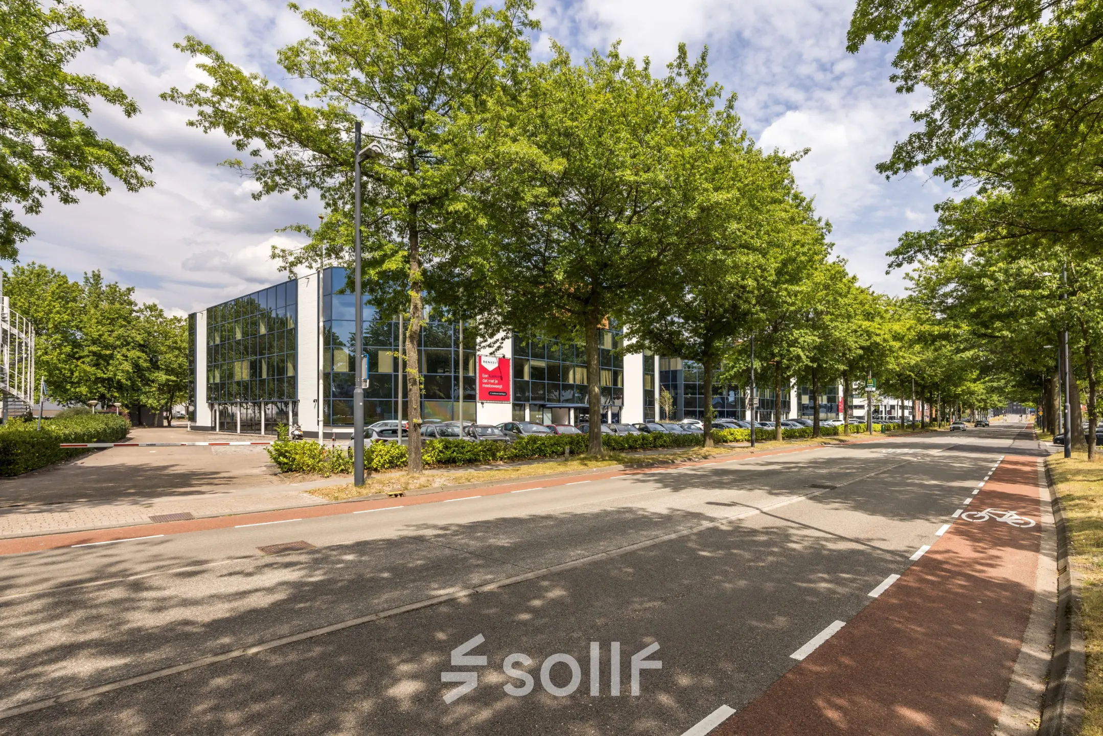 Exterior view of office space at Luchthavenweg 81, Eindhoven Airport, showcasing modern glass-fronted buildings surrounded by trees, ideal for office space rental.