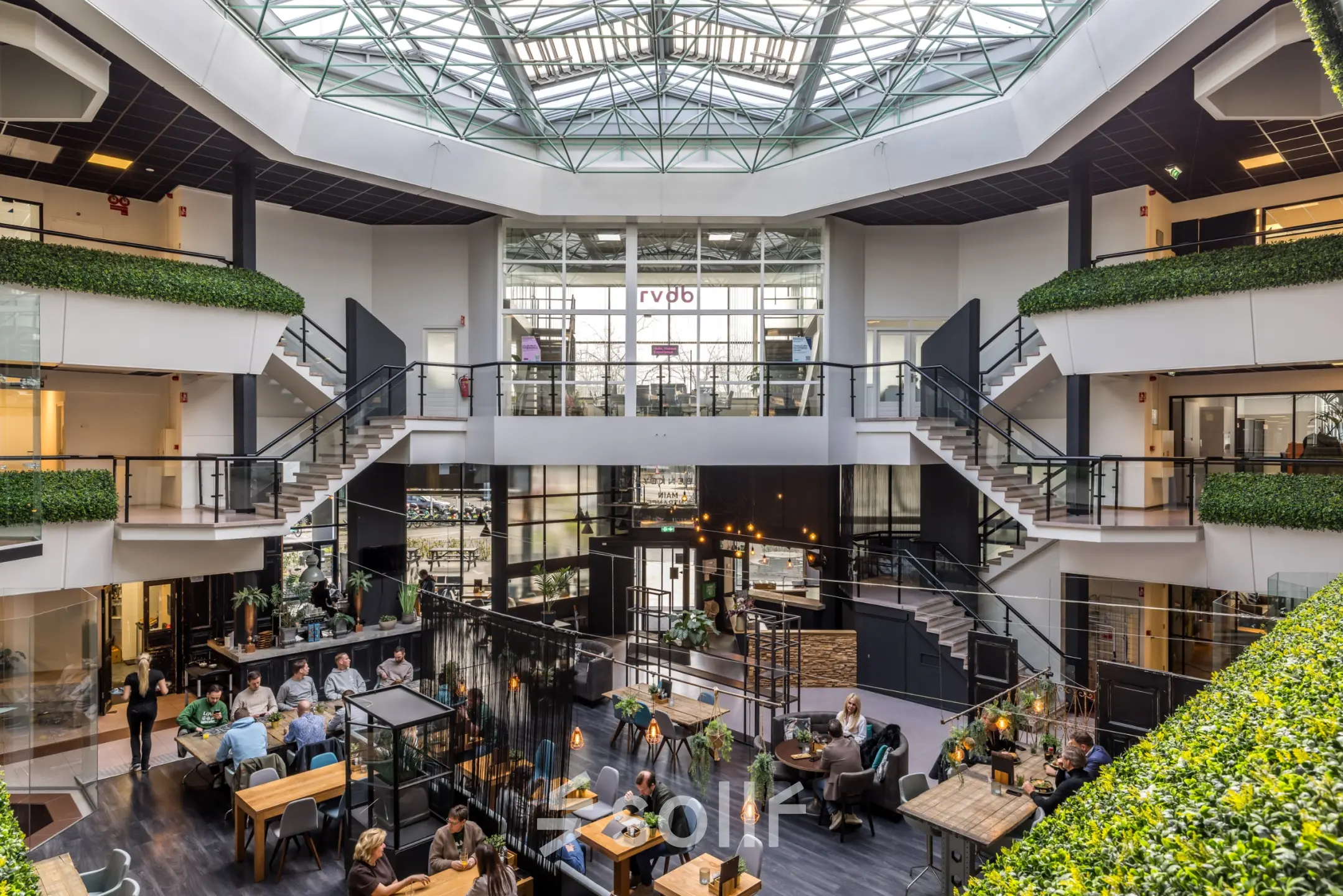Spacious office to rent at Luchthavenweg 81, Eindhoven Airport, featuring an open-floor plan with multiple individuals engaging in business conversations and activities, ideal for office space rental.