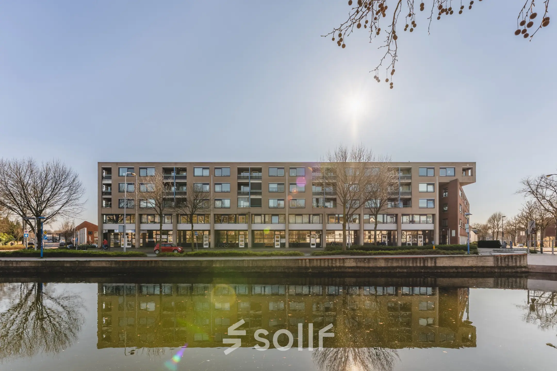 Exterior view of office building at Kanaaldijk-Zuid 19, Eindhoven Center, suitable for office space rental, with canal reflection and clear sky.