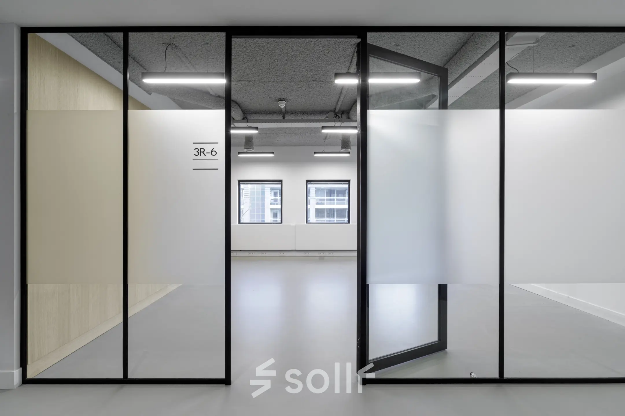 A modern office space rental in Eindhoven Center with frosted glass partitions and large windows offering natural light, suitable for businesses looking to rent office space.