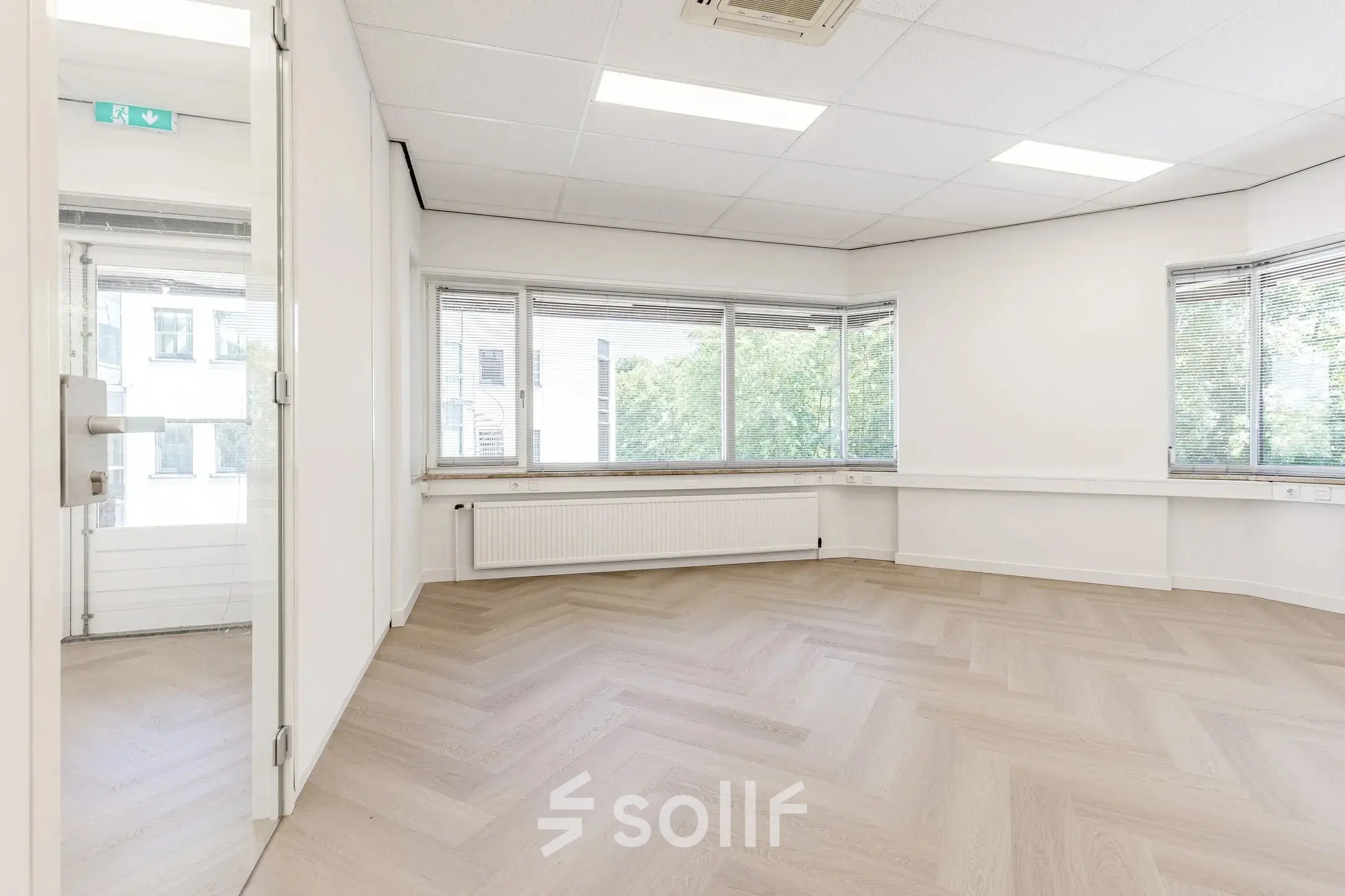 Spacious and bright office space with large windows and herringbone flooring, available for rent in Eindhoven De Hurk.