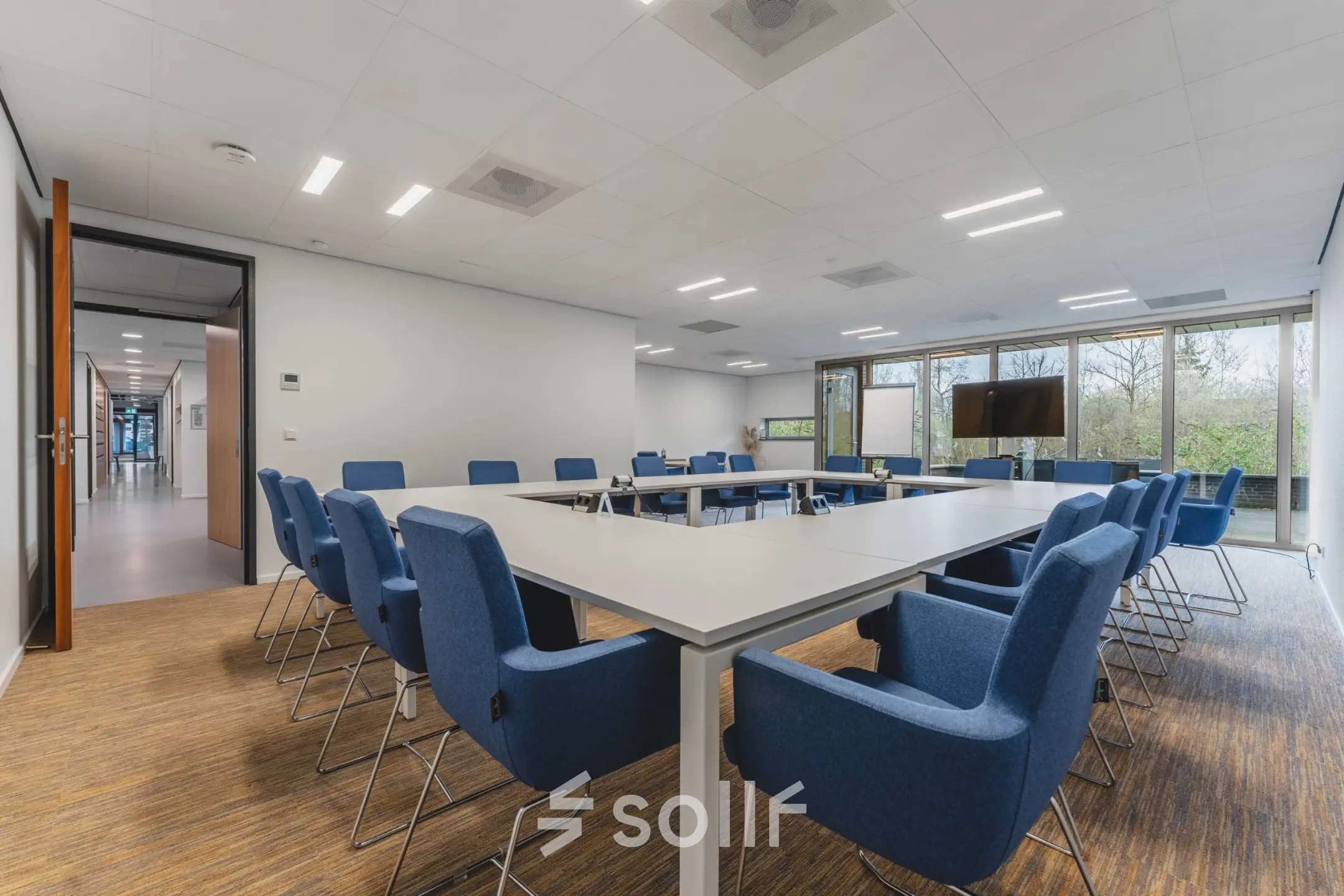 Spacious conference room with a large table surrounded by blue chairs, ideal for office space rental at Hurksestraat 60, Eindhoven De Hurk.