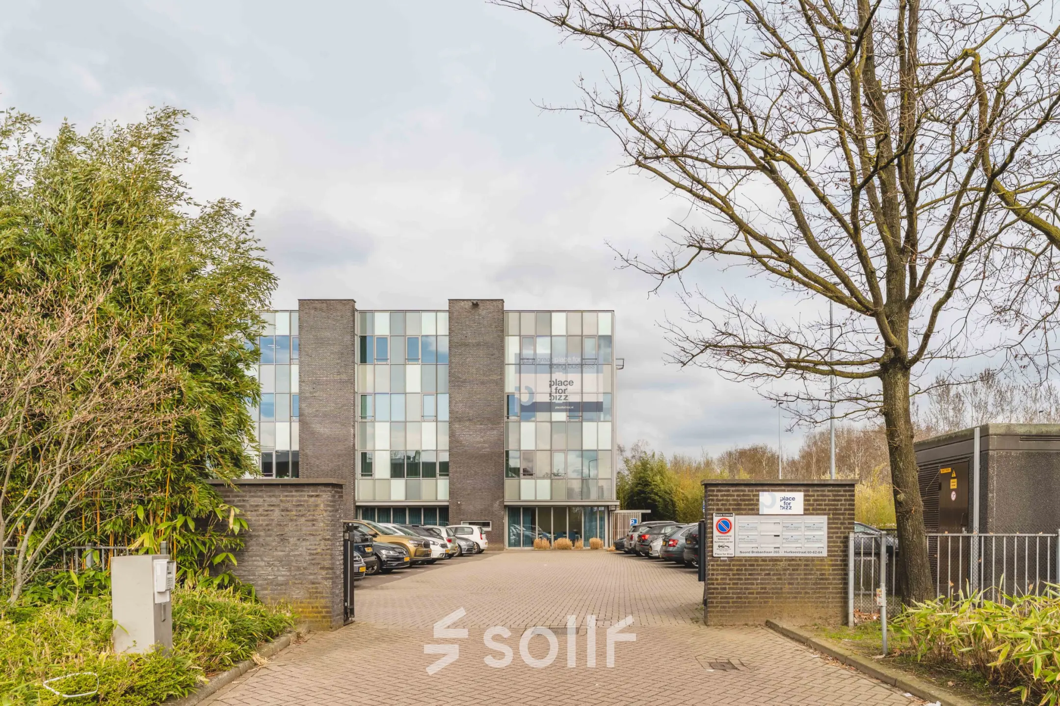 Exterior view of an office building at Hurksestraat 60, Eindhoven De Hurk, showing the entrance and parking area for office space rental.