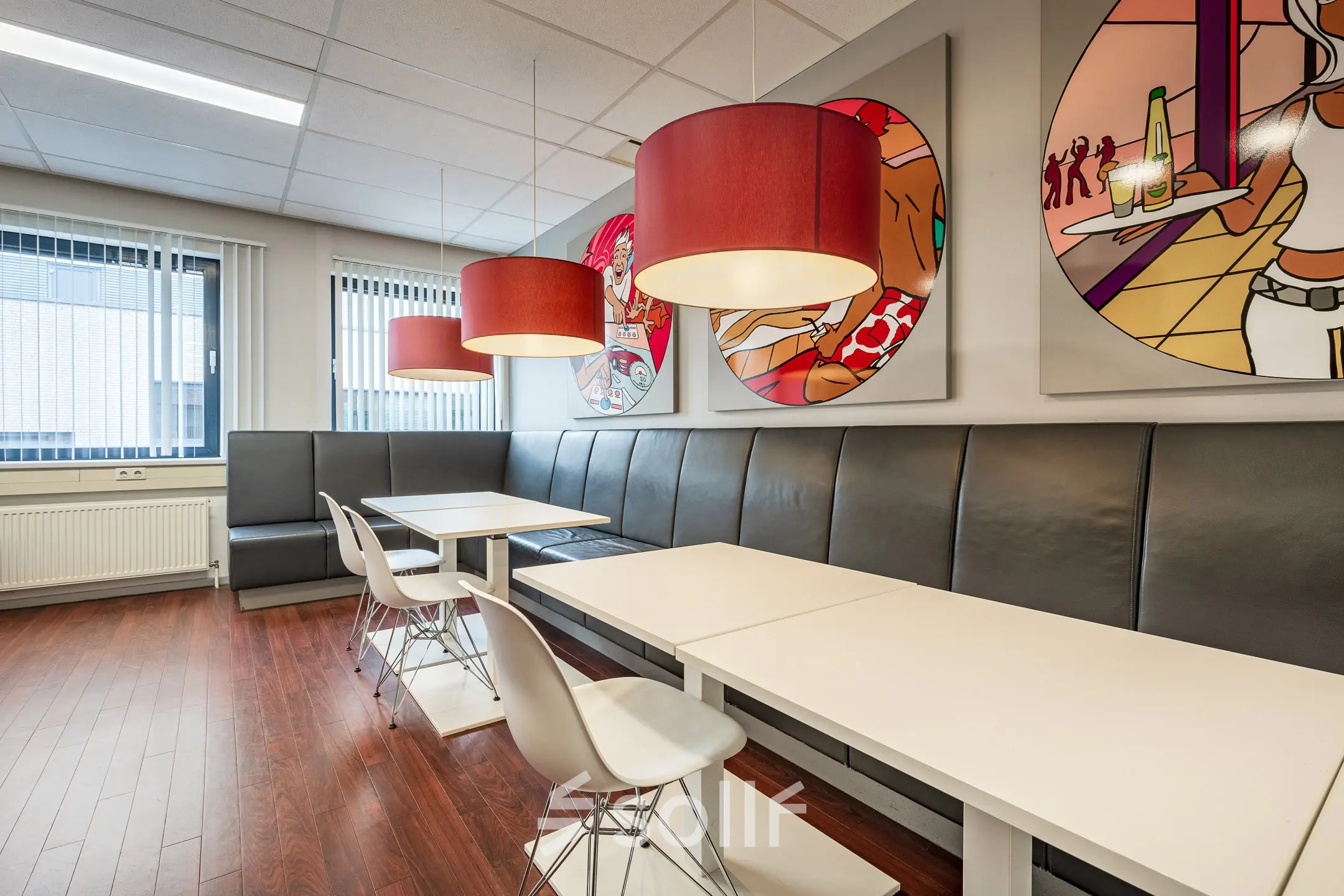 Modern office space in Eindhoven De Hurk featuring artistic wall decor, sleek tables, and contemporary pendant lighting, available for office space rental.