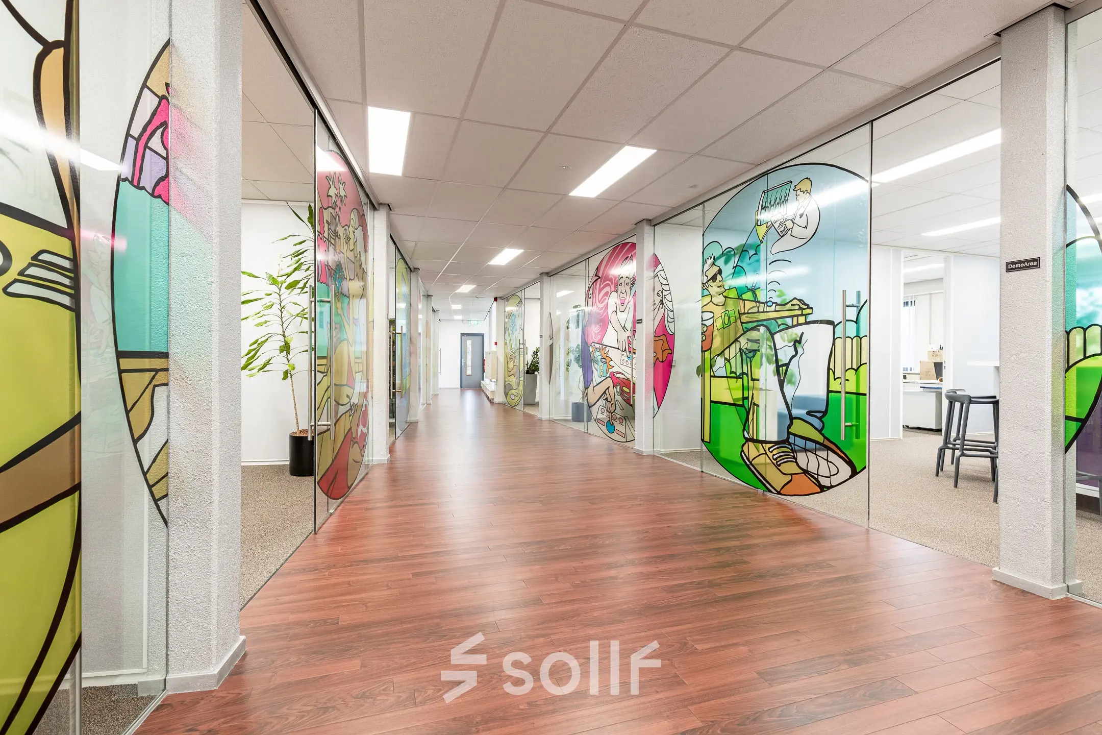 Vibrant office space at Meerenakkerplein 11-20, Eindhoven De Hurk, featuring colorful stained glass partitions and wooden floors. Ideal for office space rental.