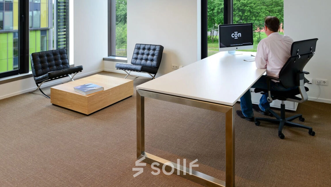 Modern office space at High Tech Campus 10, Eindhoven featuring sleek furniture with a professional working at a desk, ideal for office space rental.