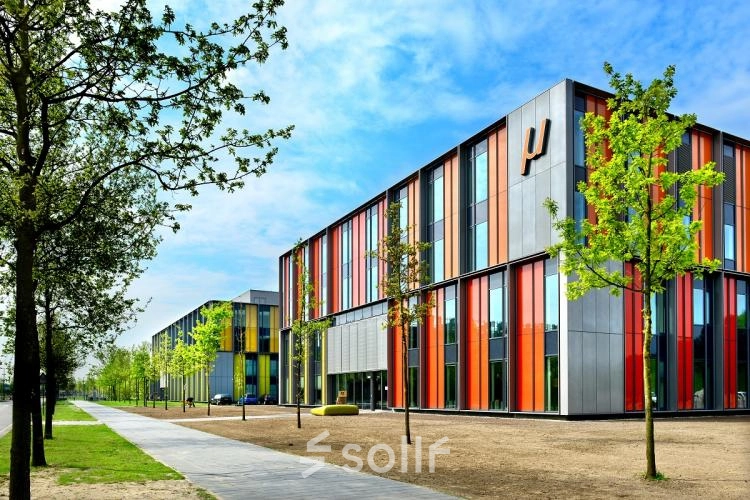 Exterior of Eindhoven High Tech Campus at High Tech Campus 10, showcasing modern, colorful architecture surrounded by trees and a clear sky, ideal location for office space rental in an innovative environment.
