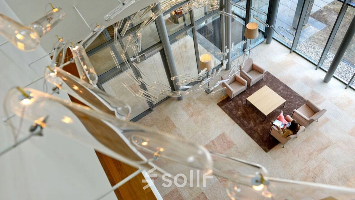 Spacious office lounge with modern seating arrangement and stylish lighting at High Tech Campus 10, Eindhoven. Ideal for informal meetings and relaxation, this space enhances your office space rental experience.