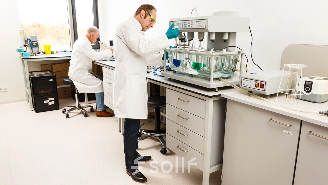 Two people in lab coats are working with scientific equipment in a clean laboratory space at High Tech Campus 10, Eindhoven. A bright and professional environment suitable for research and development activities.