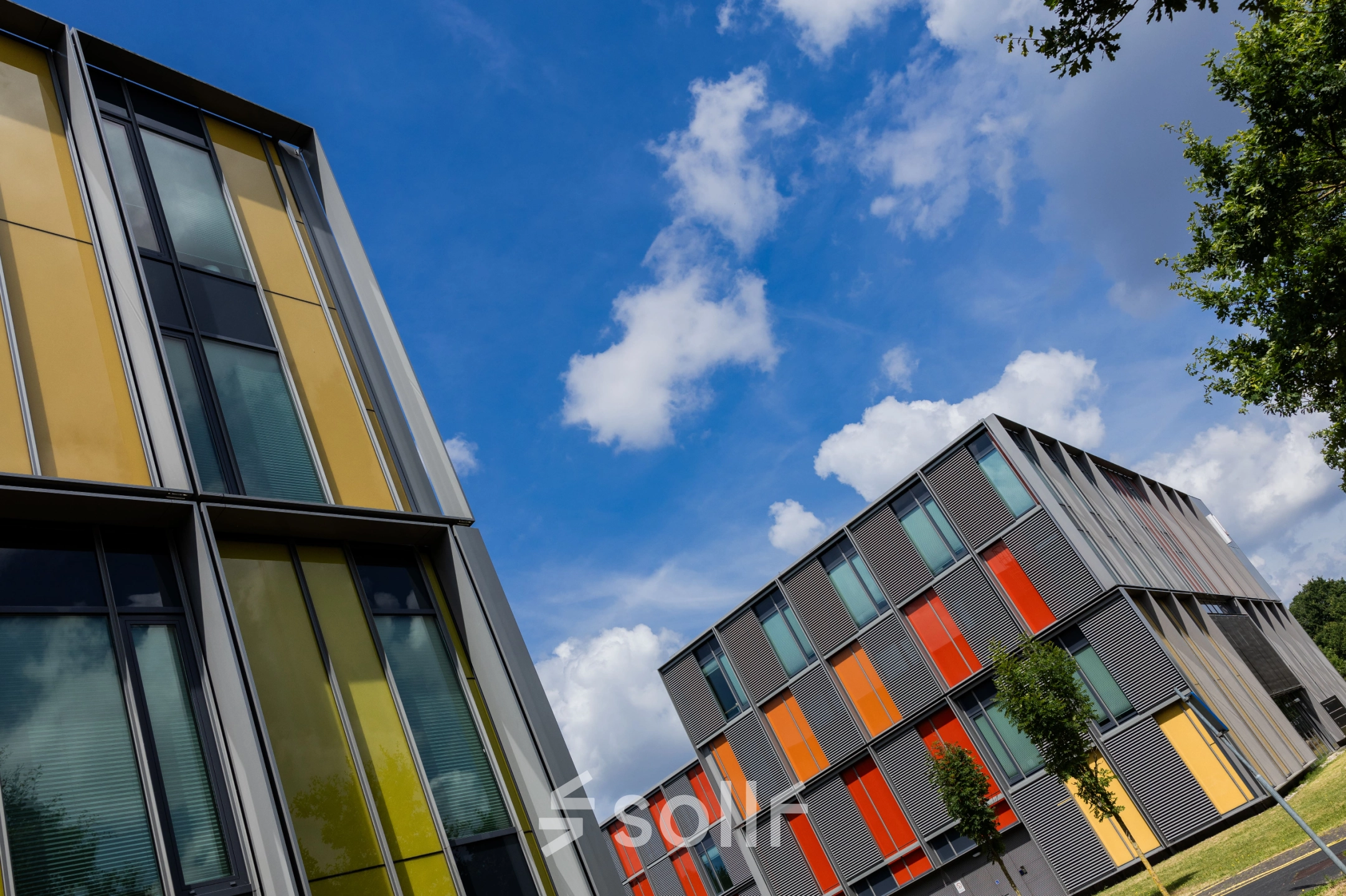 Exterior view of vibrant office buildings at High Tech Campus 9 in Eindhoven. Ideal location for office space rental, surrounded by a tech-centric environment with colorful architectural design.