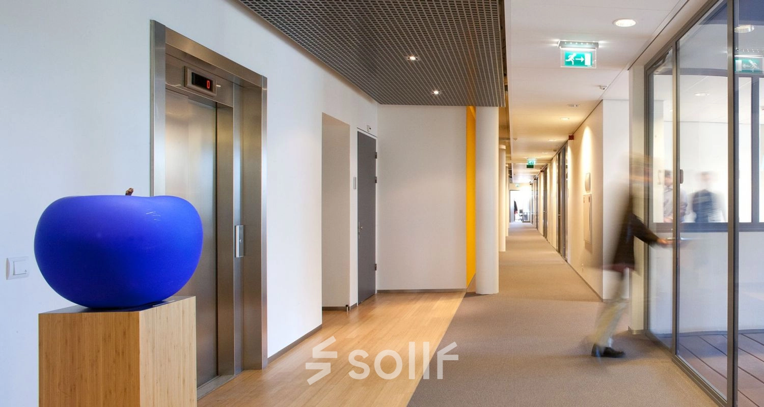 Modern interior hallway at High Tech Campus 9, Eindhoven, featuring a blue sculpture and sleek design, ideal for office space rental. The corridor exudes a professional atmosphere with a contemporary touch.