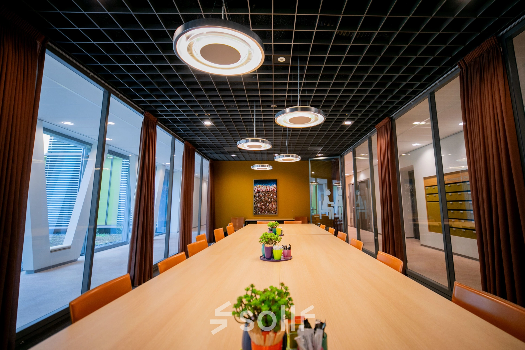 Spacious conference room at High Tech Campus 9, Eindhoven with modern lighting and a large table, ideal for office space rental. Surrounded by glass walls, enhancing communication and collaboration.