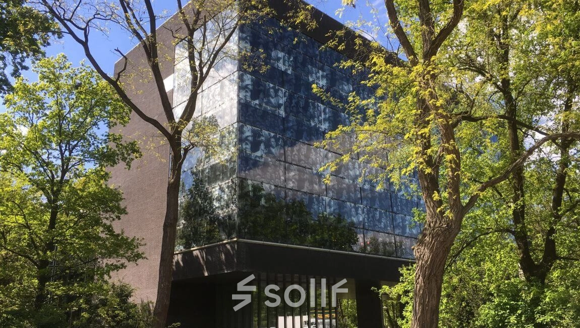 Modern office building at TU campus, De Zaale 11, Eindhoven High Tech Campus, surrounded by lush trees, featuring sleek glass windows. Ideal for office space rental.