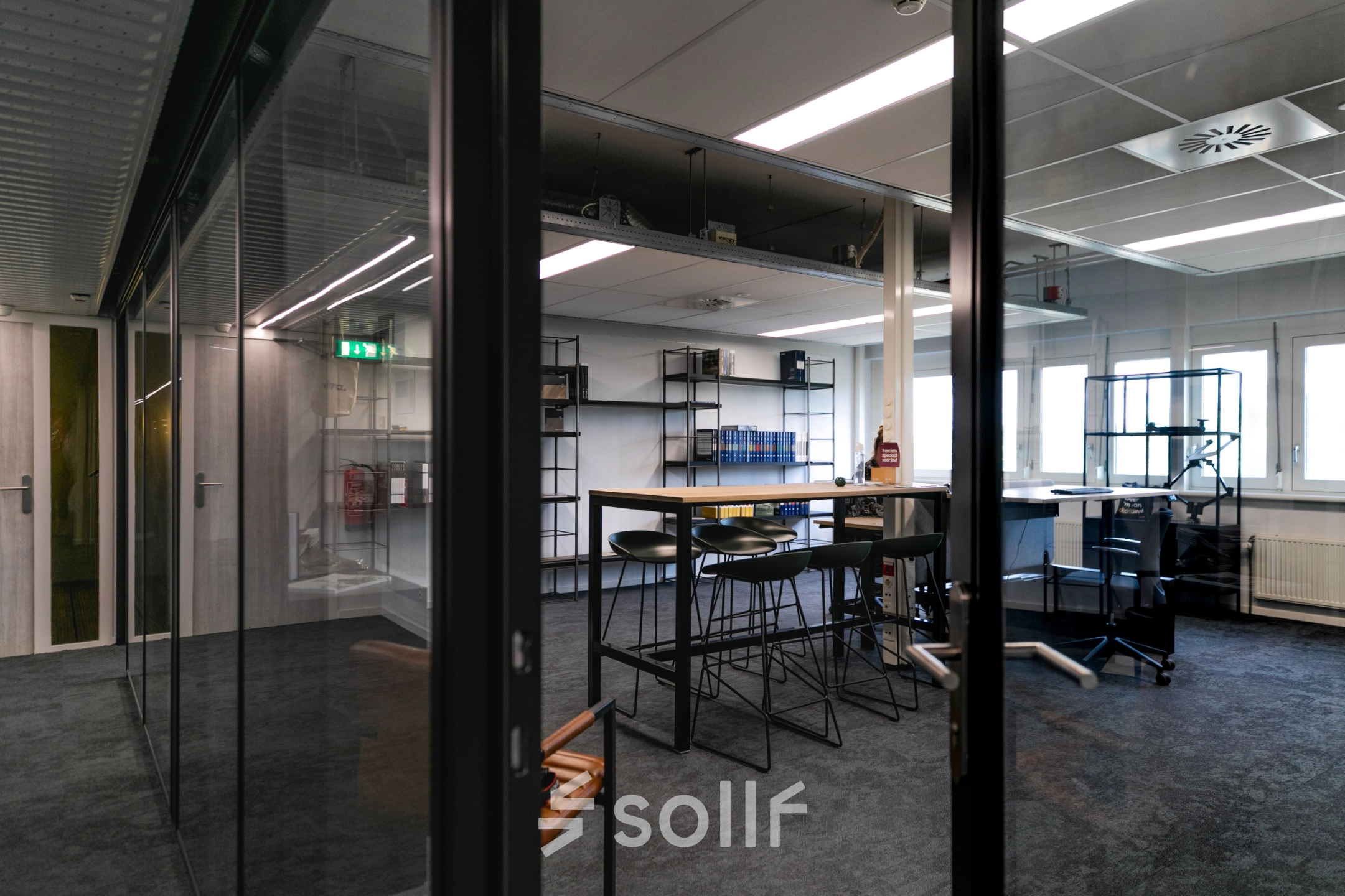 Modern office space featuring glass partitions and high tables, perfect for collaborative work. Located at TU campus, De Zaale 11, in Eindhoven High Tech Campus, this bright space is available for office space rental.