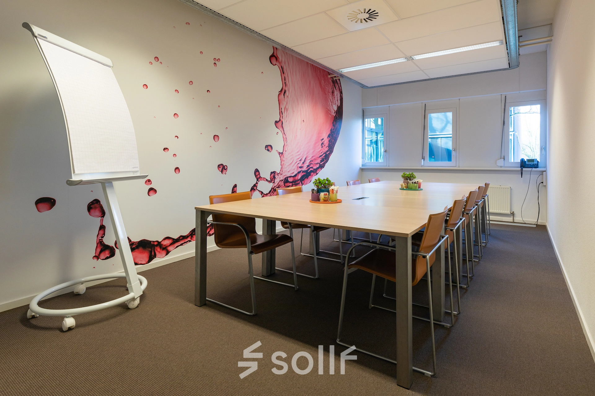 Modern conference room with a large wooden table, stylish chairs, and a flipchart, ideal for office space rental at TU campus, De Zaale 11, Eindhoven High Tech Campus.