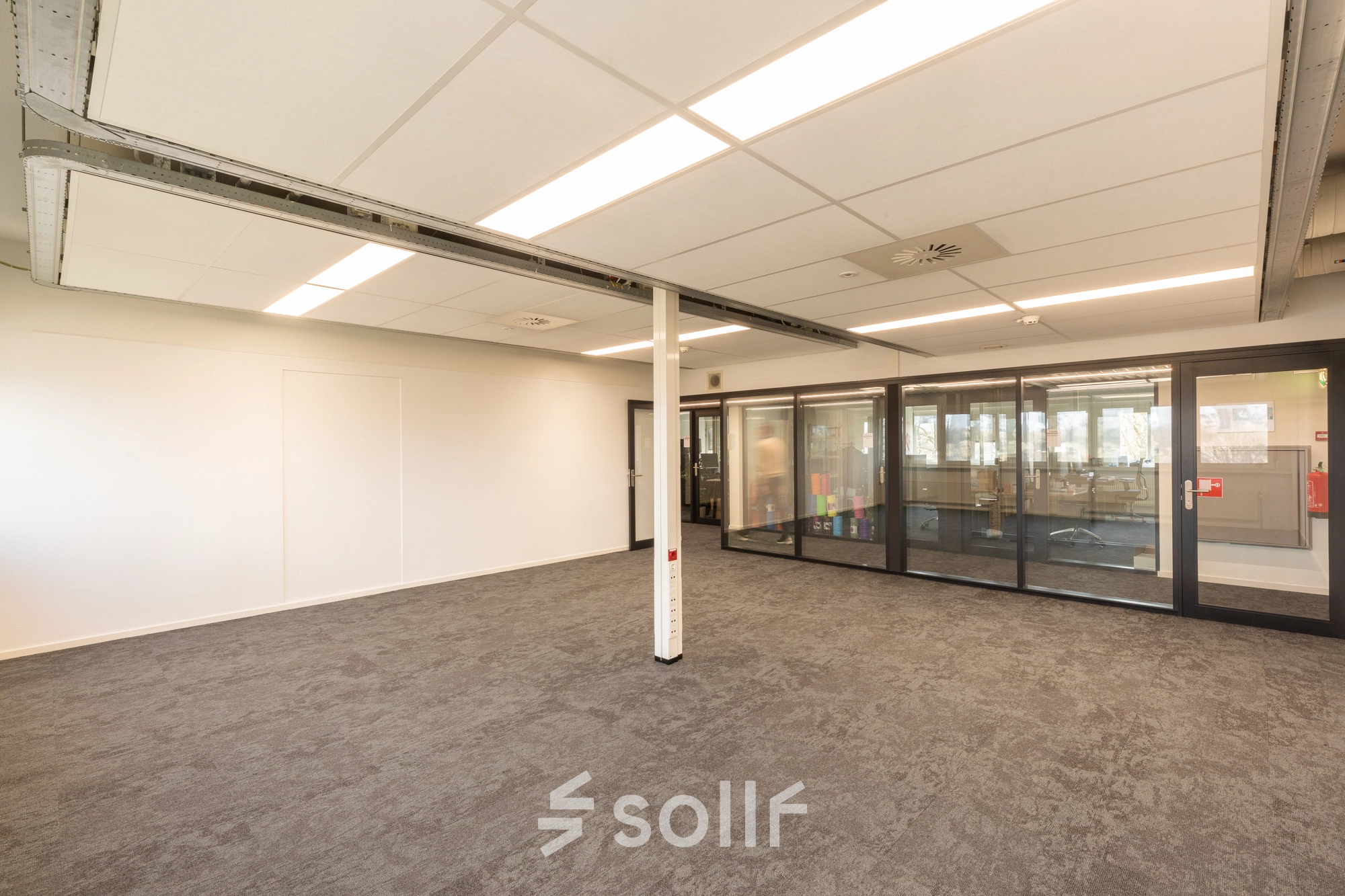 Interior view of an unfurnished office space with carpet flooring and ceiling lights at TU campus, De Zaale 11, Eindhoven High Tech Campus, suitable for office space rental.