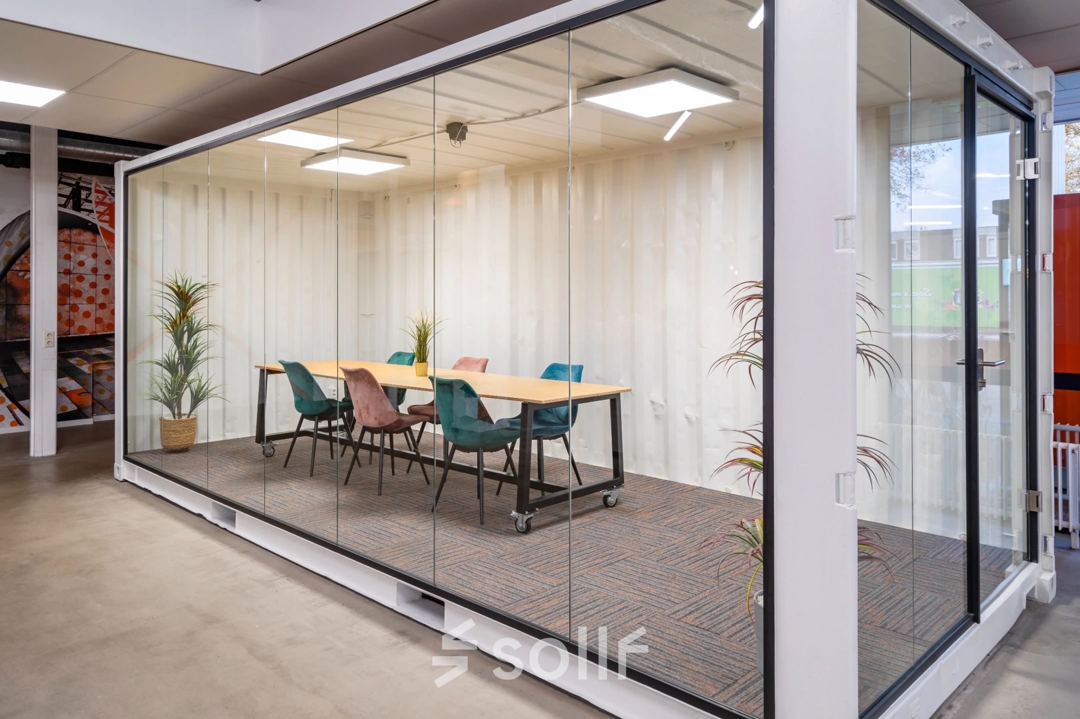 Modern conference room in Eindhoven North, featuring a sleek glass-walled design and colorful chairs, available for office space rental at Tarasconweg 2.