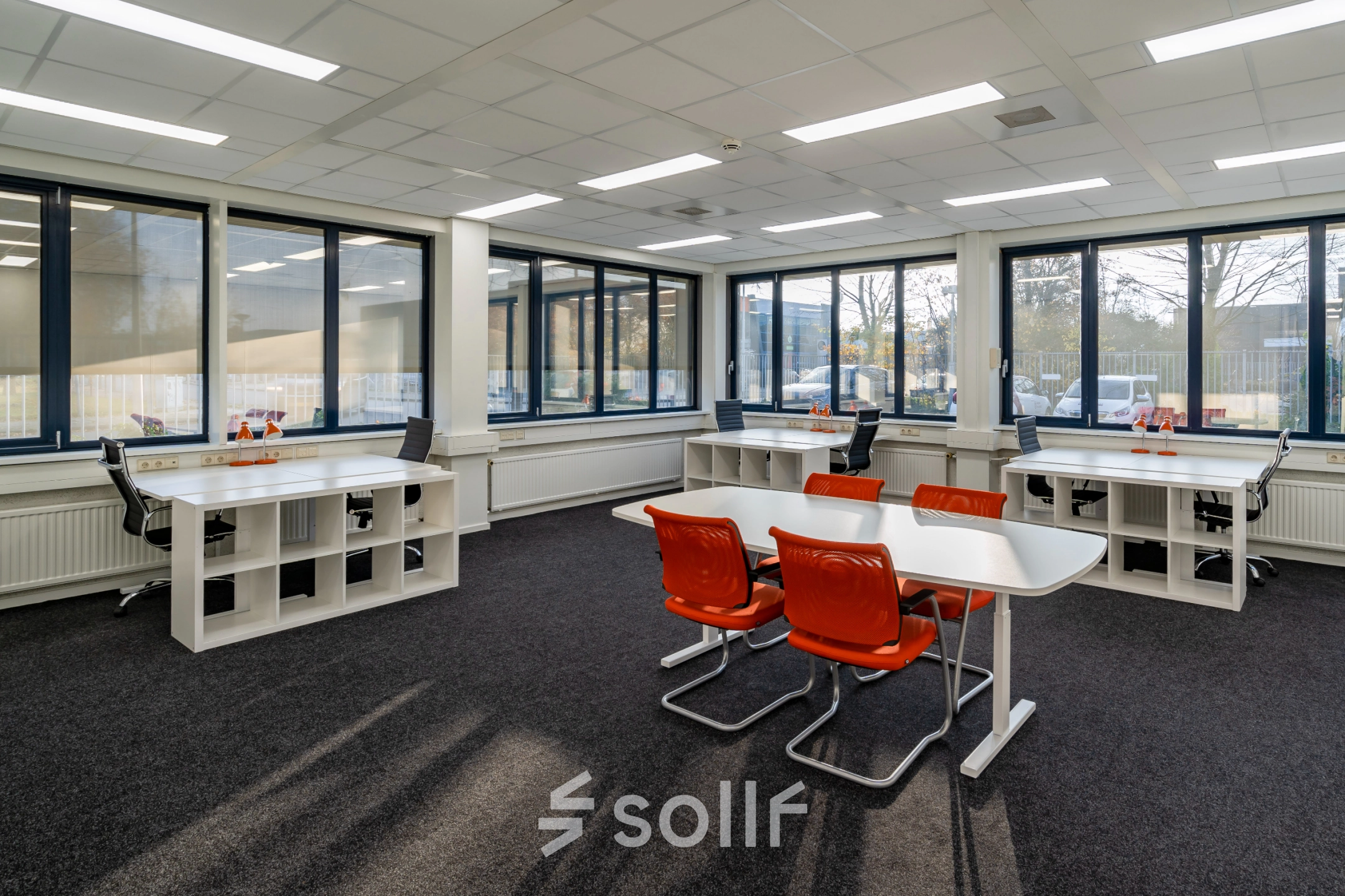 Bright office space with rows of white desks and orange chairs at Tarasconweg 2, Eindhoven North. Large windows provide ample natural light, ideal for office space rental.
