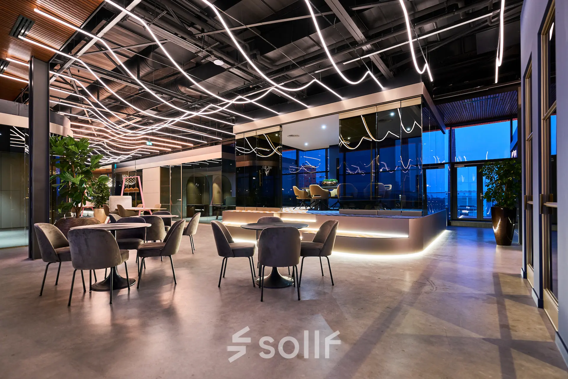 Modern office space with sleek lighting, furnished with round tables and chairs, creating a dynamic environment for renters at Achtseweg Zuid 159R, Eindhoven Strijp-S.