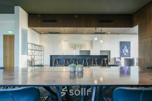 Chic office space rental in Eindhoven Strijp-S with a modern interior featuring a large table, stylish barstools, and contemporary decor at Achtseweg Zuid 159R.