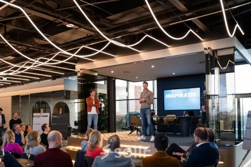 A modern, furnished office space in Eindhoven Strijp-S with people attending a presentation, ideal for office space rental.