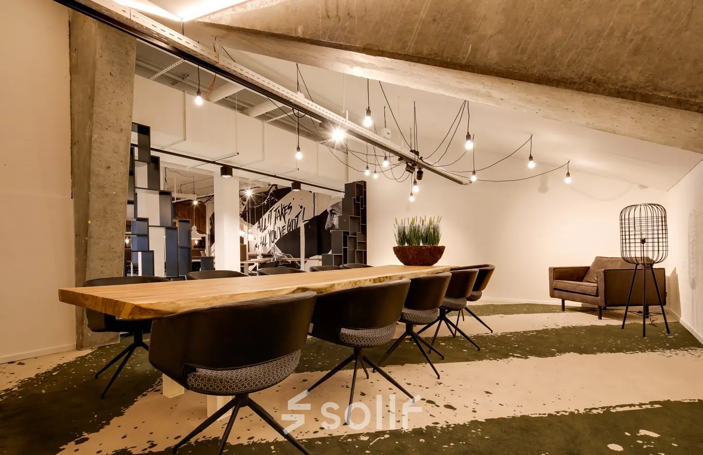 Modern office space at Frederiklaan 10E in Eindhoven Strijp-S with a long wooden table and chairs, suitable for a dynamic workspace environment. Ideal for office space rental.