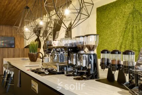 Modern office lounge area at Frederiklaan 10E, Eindhoven Strijp-S, featuring coffee machines and stylish lighting fixtures, ideal for office space rental.