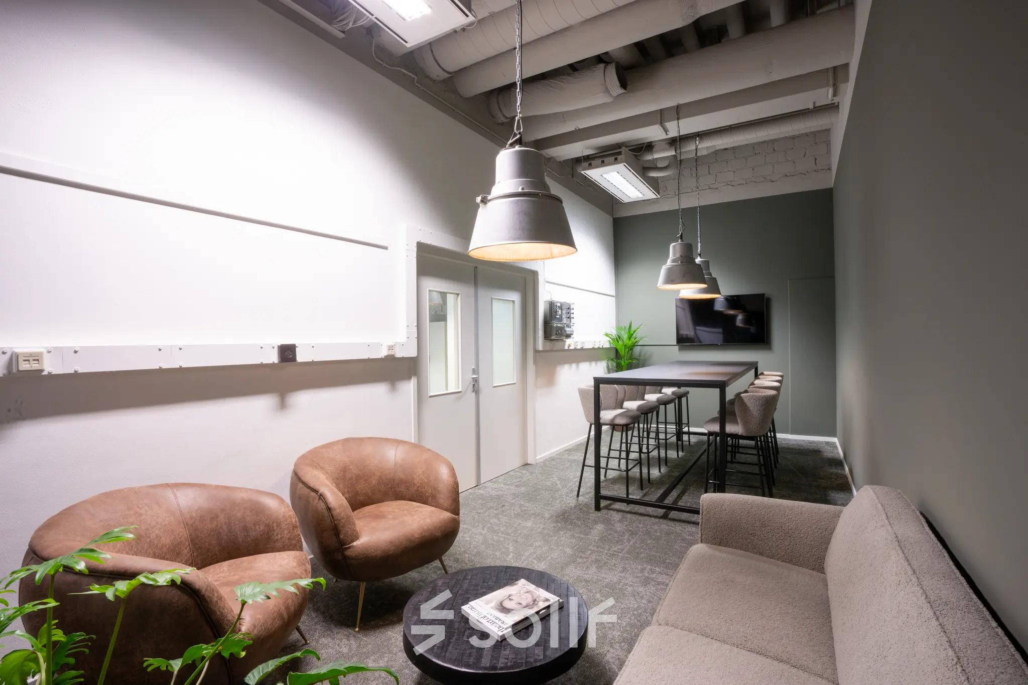 Furnished office space rental at Torenallee 20, Eindhoven Strijp-S, featuring modern seating with bar stools and a TV in a cozy setting.