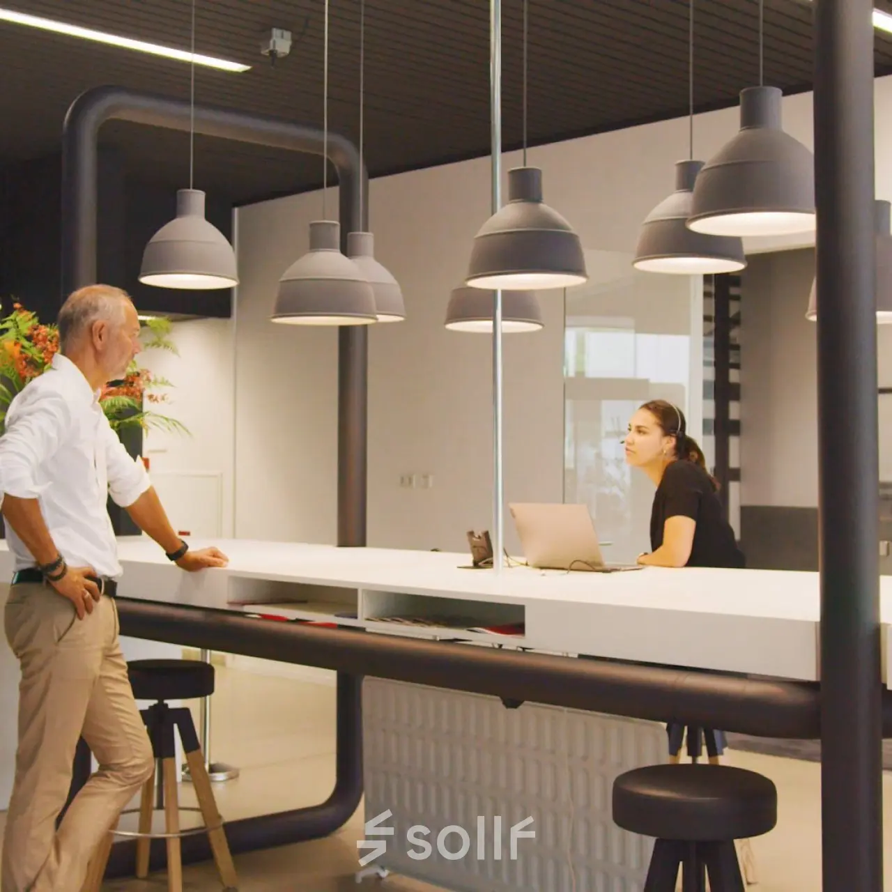 Office space rental area at Eindhoven Strijp-S with a man and woman interacting near a modern reception desk.