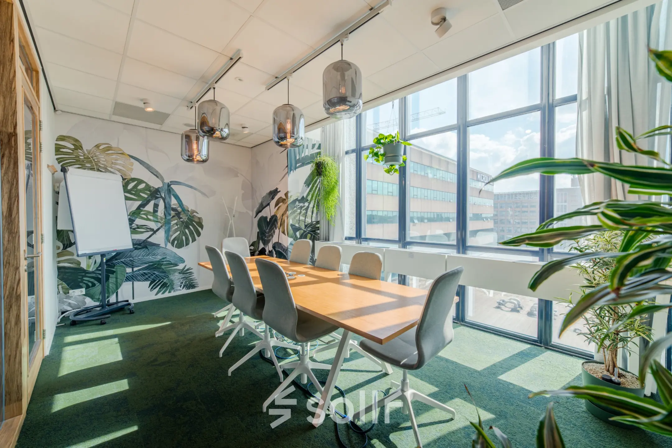 Bright conference room with natural light, green accents, and a large table, showcasing an inviting office space rental option.