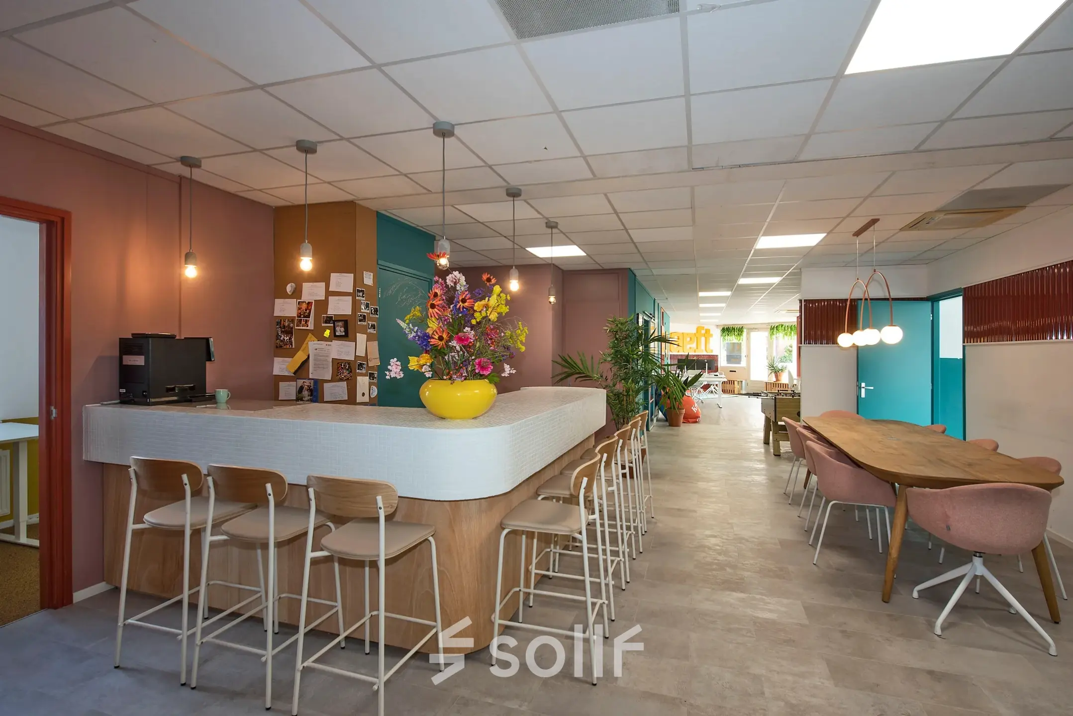 Bright office space to rent at Boddenkampsingel 95, Enschede, featuring a furnished interior with a long table, bar stools, and colorful decor, ideal for workspaces.