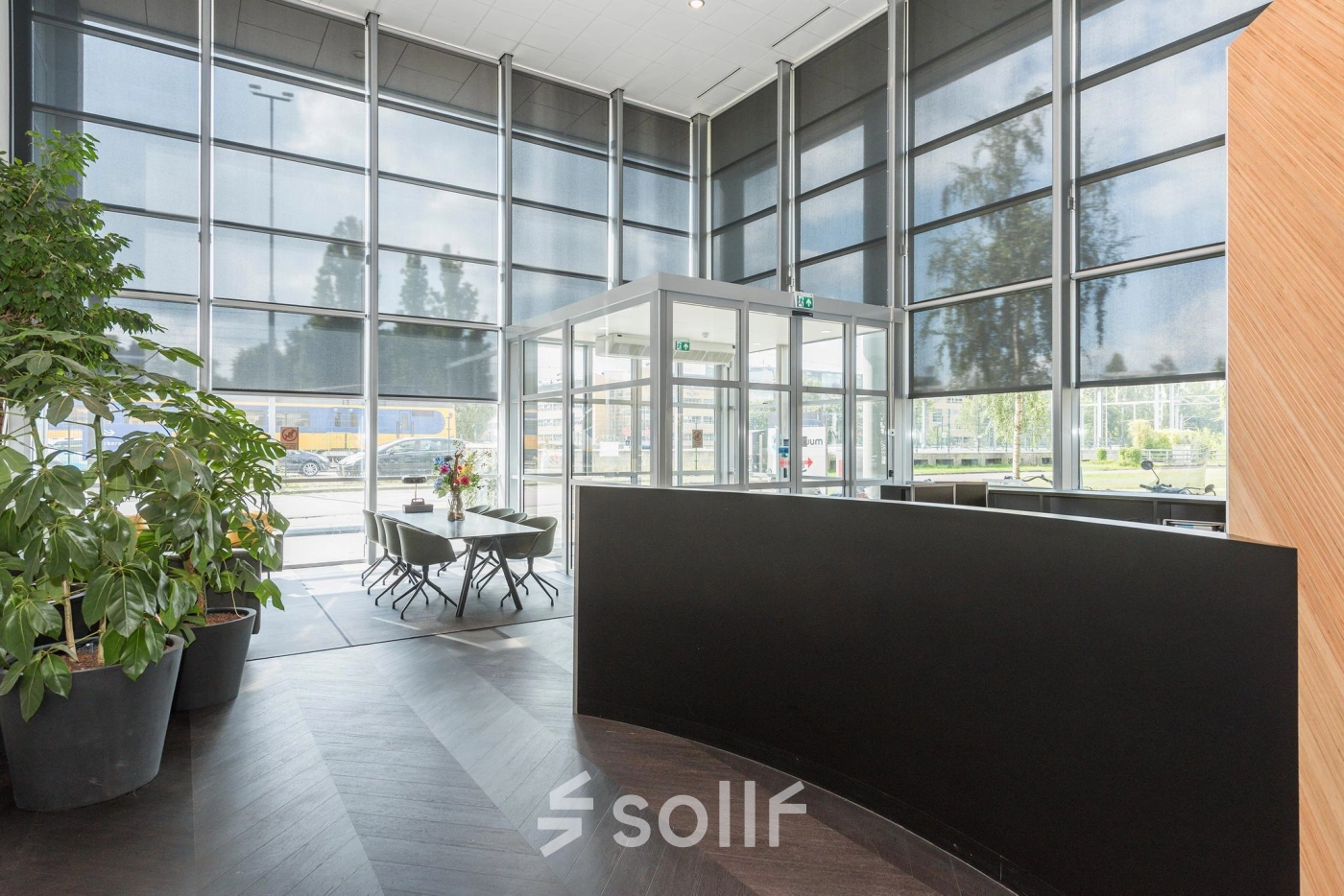 Spacious office entrance with large windows, sleek reception desk, and potted plants at Brandweerstraat 20-30, Enschede. Ideal for businesses seeking professional office space rental.